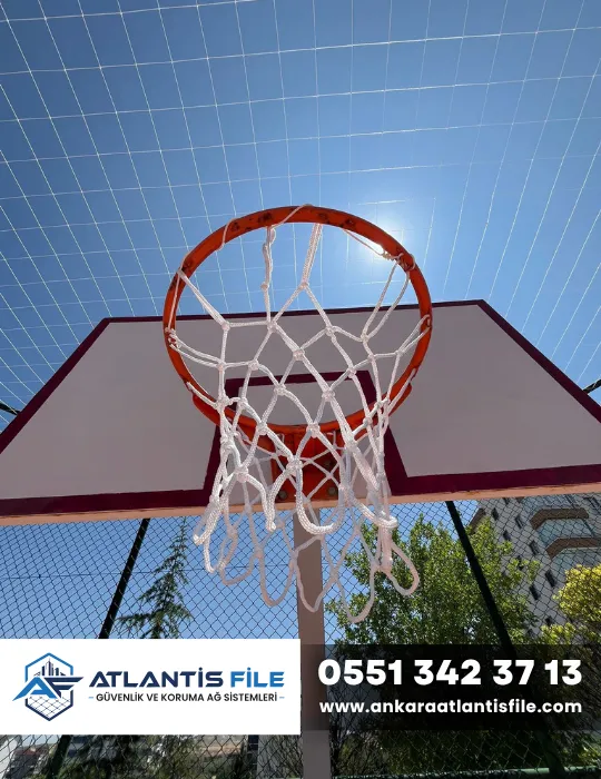 Açık basketbol sahasında potaya takılmış beyaz basketbol filesi ve üst koruma filesi