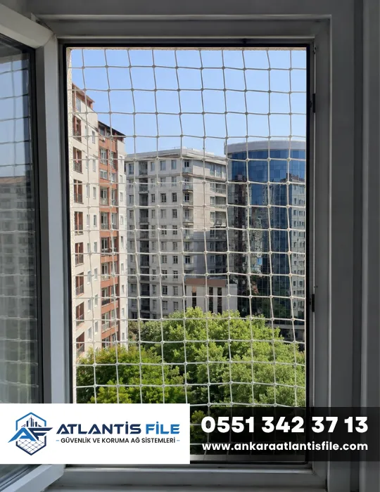 Yüksek katlı binada açık pencereye uygulanmış beyaz pencere güvenlik filesi
