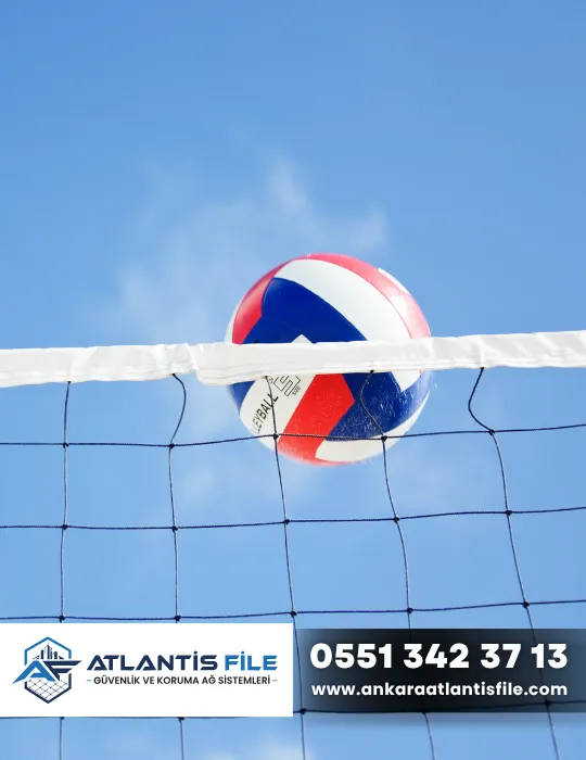 Voleybol sahasında kullanılan siyah voleybol filesi ve file üzerinden geçen voleybol topu